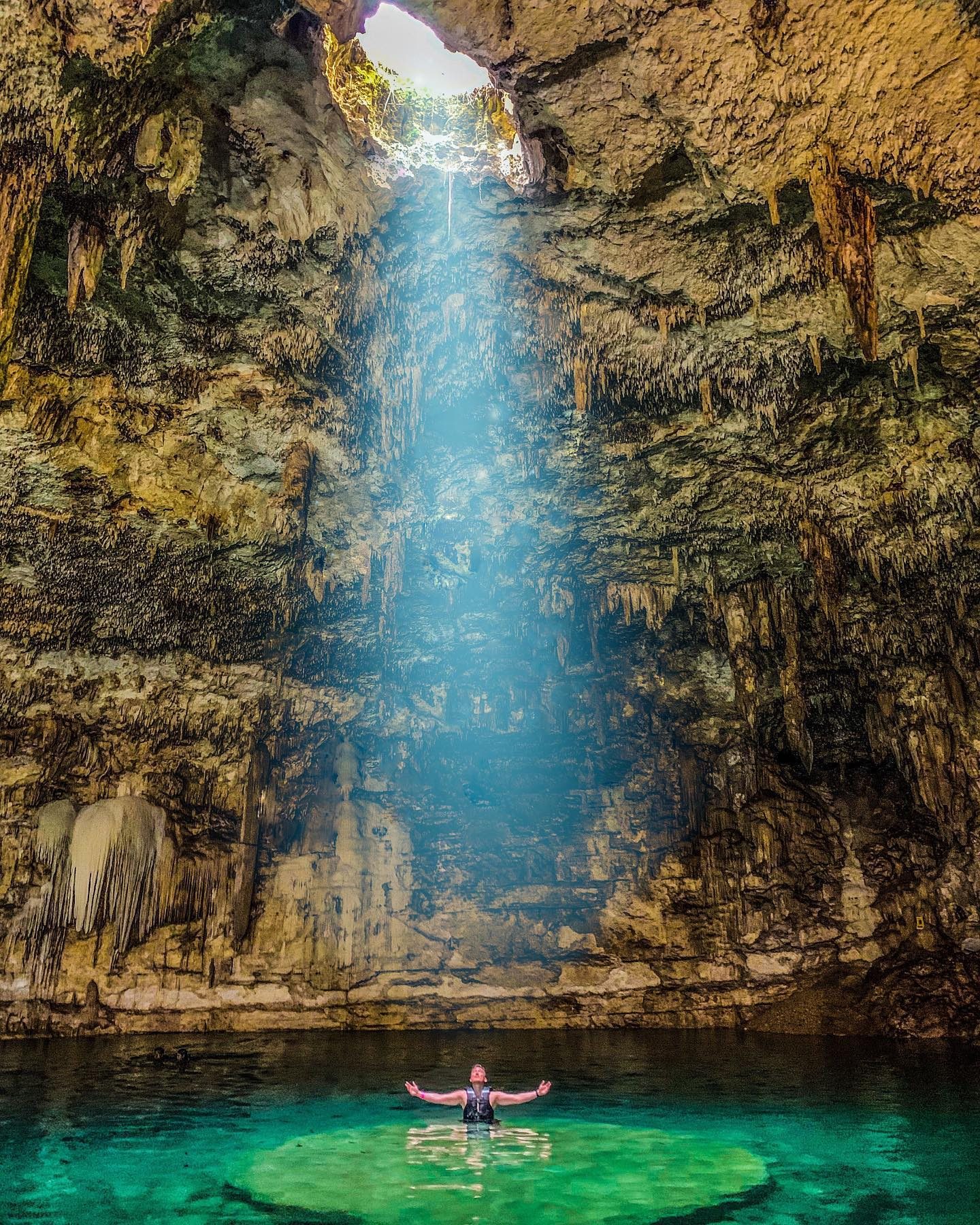 Arthur standing in a cenote pool under a shaft of light