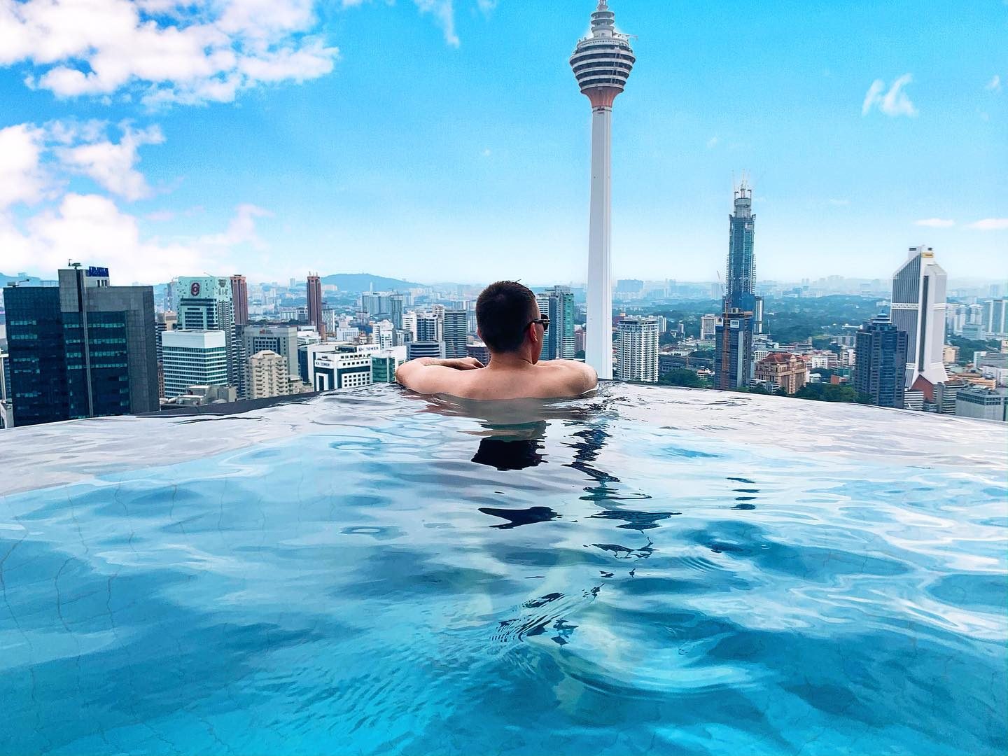 Arthur in a rooftop infinity pool overlooking the Kuala Lumpur skyline and KL Tower