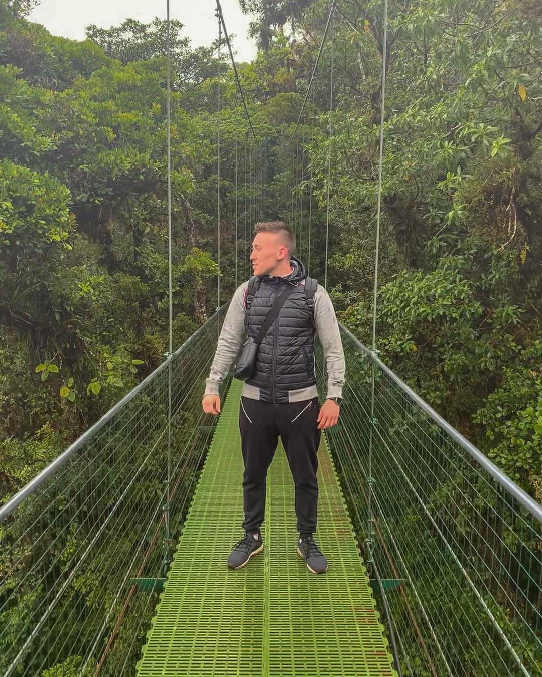 Arthur standing on a jungle suspension bridge