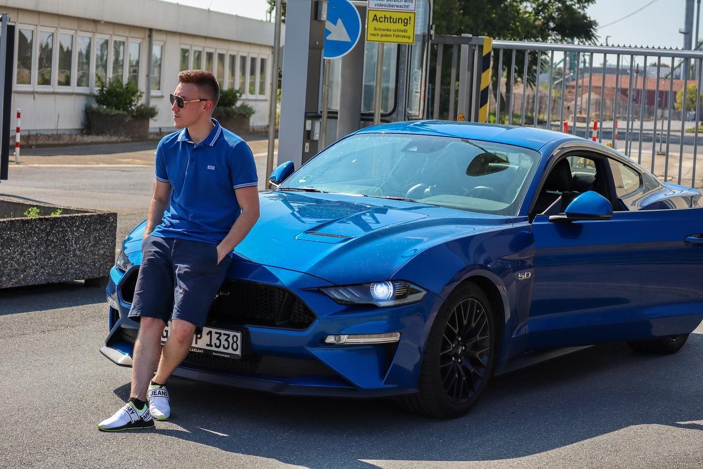 Arthur leaning against a blue Ford Mustang