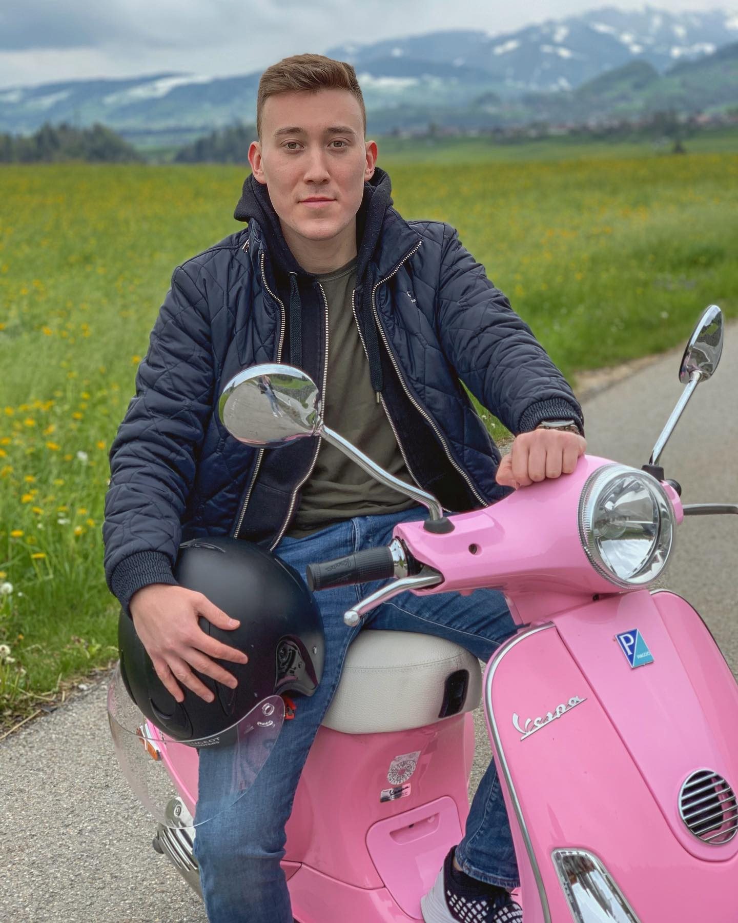 Arthur on a pink Vespa in an alpine meadow